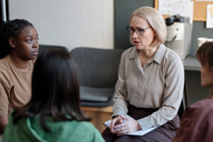 Trauma counselor near me leading a support group session with adult clients in a calm therapy setting.